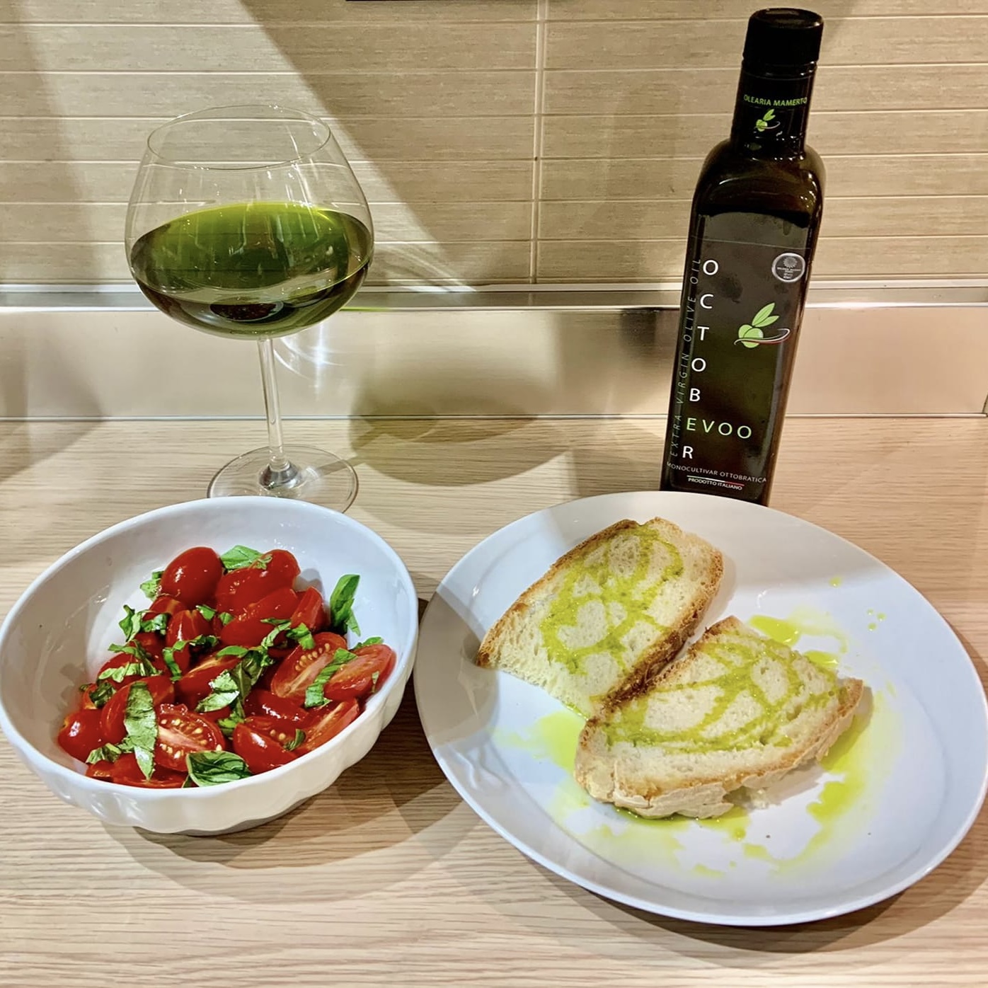 bicchiere e bottiglia di olio con bruschette e pomodori